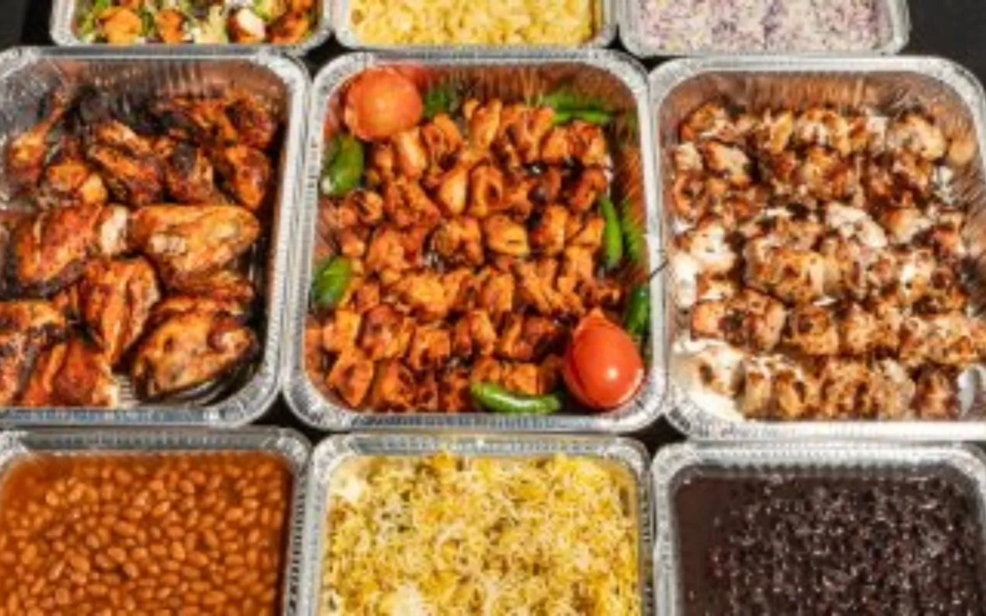 BBQ Toni8ht catering trays of chicken tikka, malai boti, biryani and sides laid out for an event